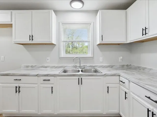 a kitchen with cabinets appliances a sink and a window