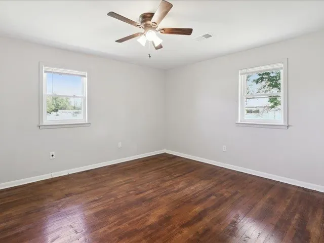 a view of an empty room with a window and wooden floor