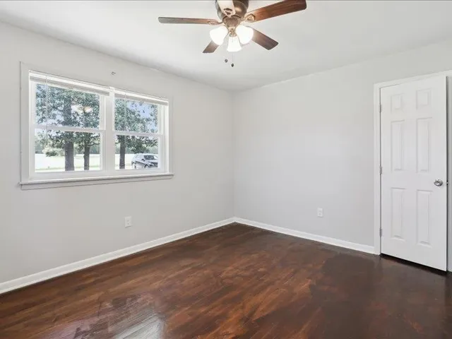 a view of an empty room with wooden floor and a window
