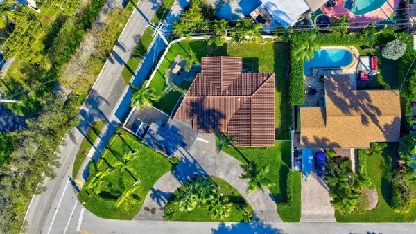 an aerial view of residential house with outdoor space and trees all around