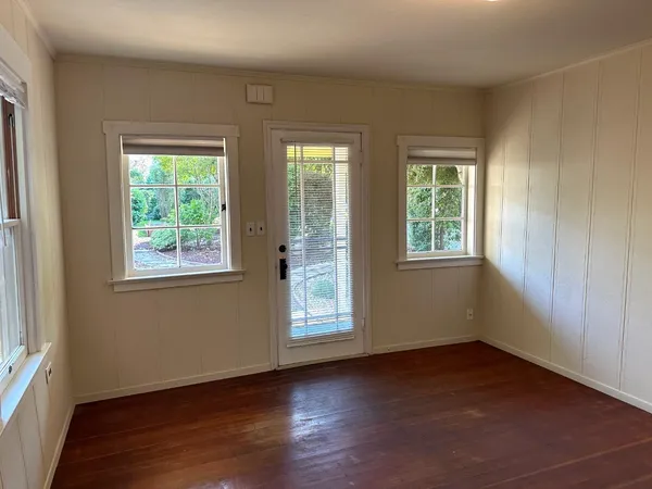 an empty room with wooden floor and windows