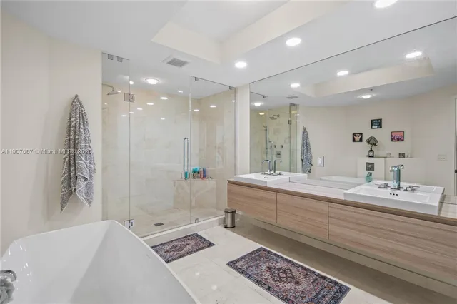 a bathroom with a double vanity sink large mirror and a bathtub