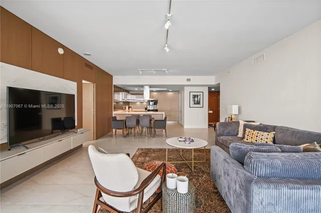 a living room with furniture a flat screen tv and kitchen view