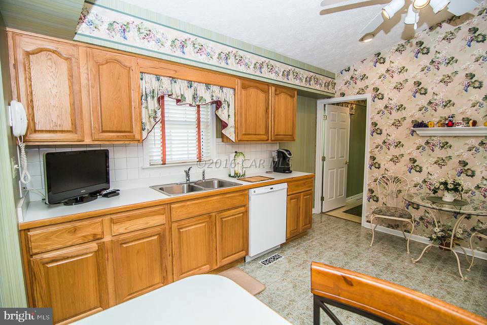 217 Windjammer Road Ocean Pines, MD 21811 - Photo 29 of 47 a kitchen with stainless steel appliances wooden cabinets a stove a sink and a microwave