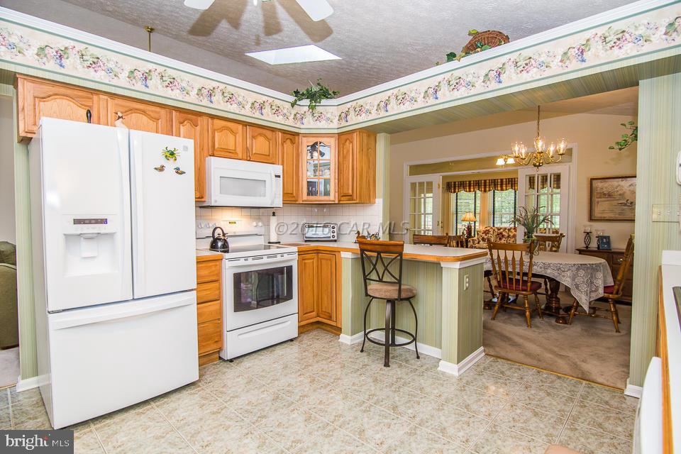 217 Windjammer Road Ocean Pines, MD 21811 - Photo 10 of 47 a kitchen with a refrigerator a stove a dining table and chairs