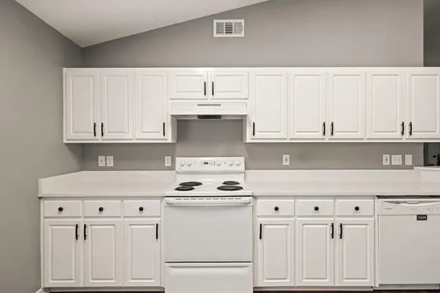 a kitchen with white cabinets and white appliances