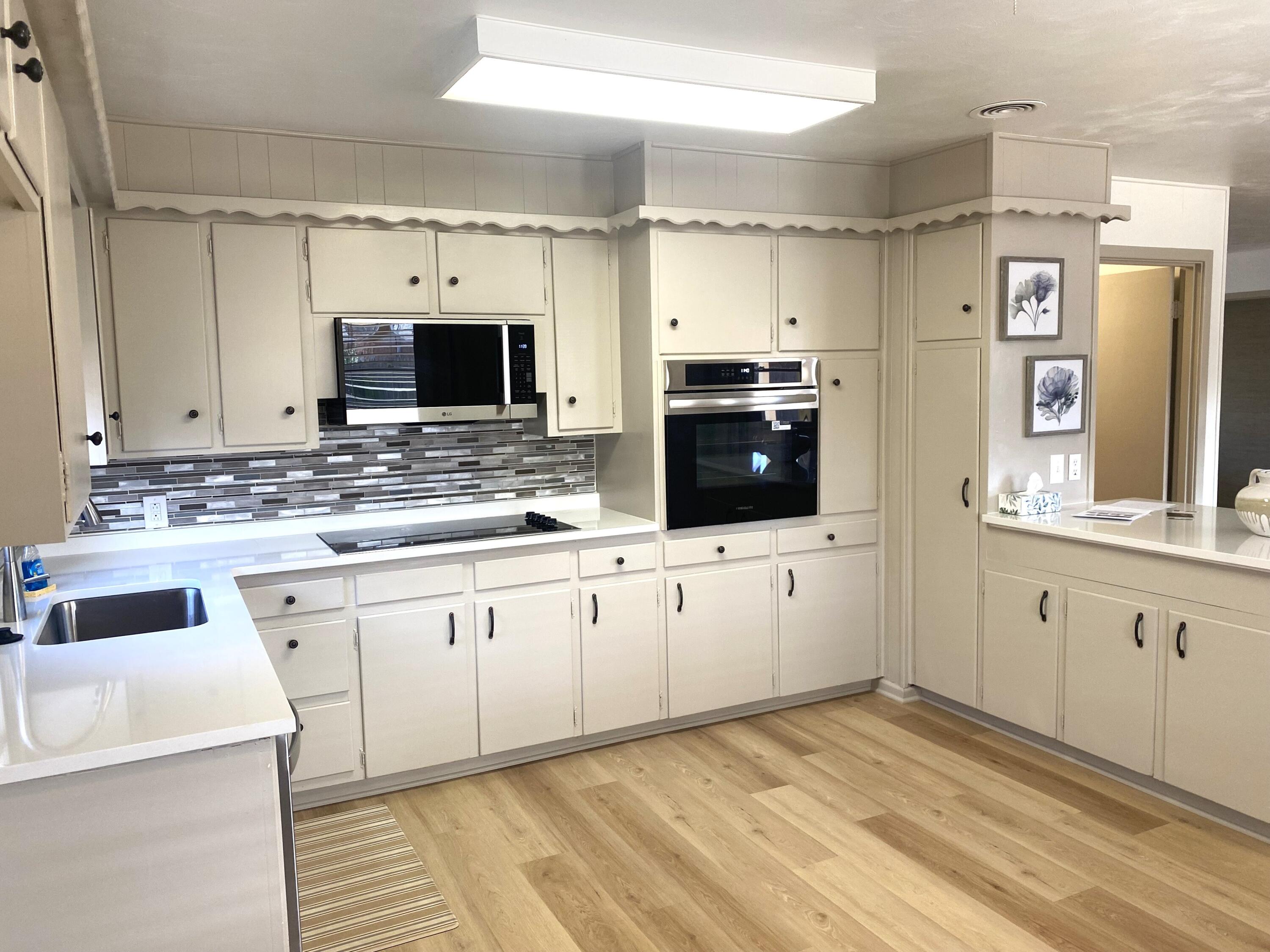3415 58th Street Lubbock, TX 79413 - Photo 12 of 38 a large kitchen with granite countertop a sink and white cabinets