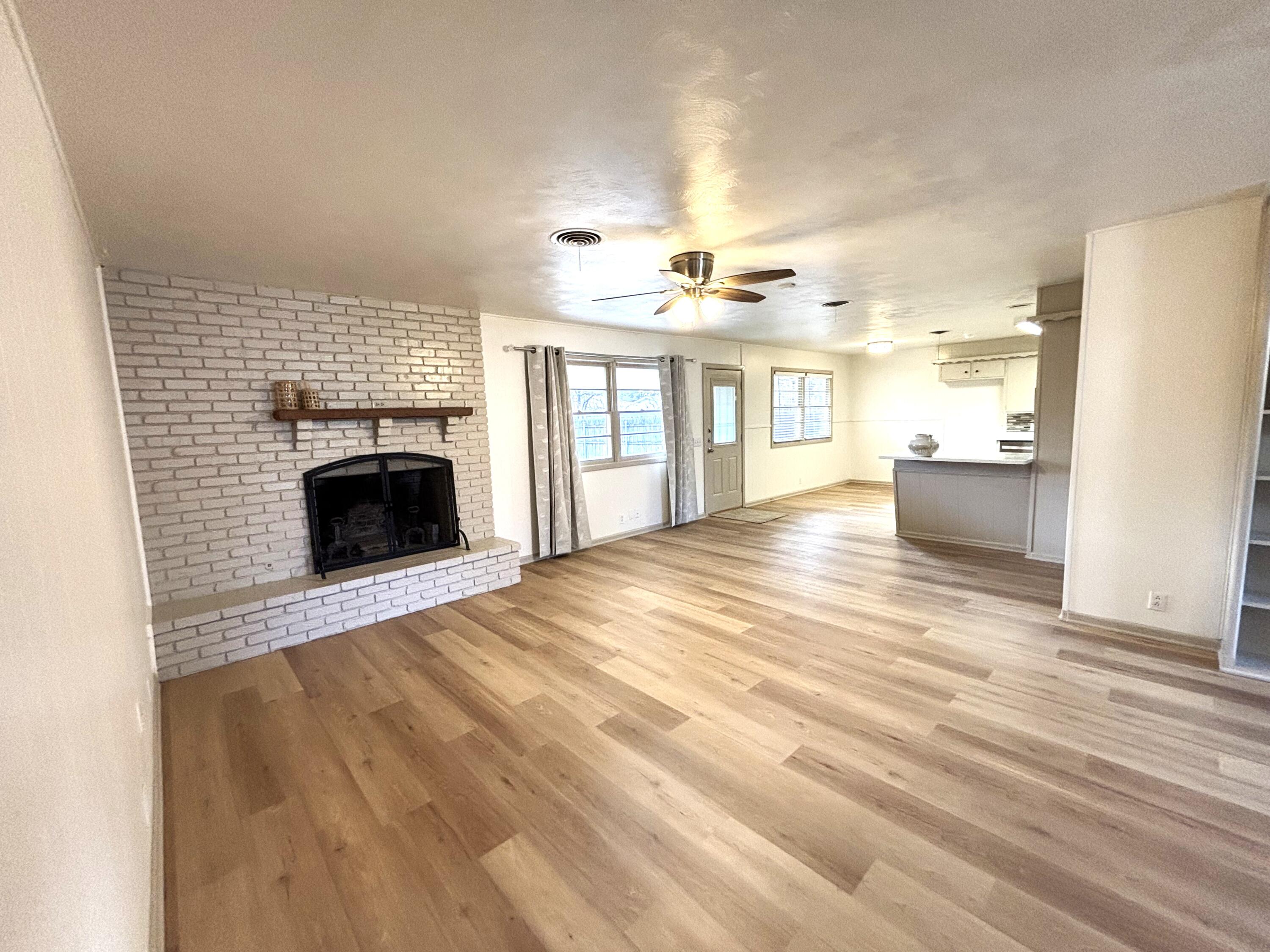 3415 58th Street Lubbock, TX 79413 - Photo 5 of 38 an empty room with wooden floor fireplace and windows