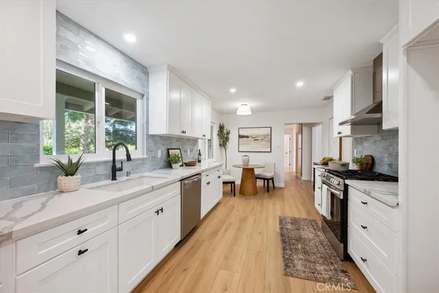 a large kitchen with stainless steel appliances granite countertop a lot of counter space and wooden floors
