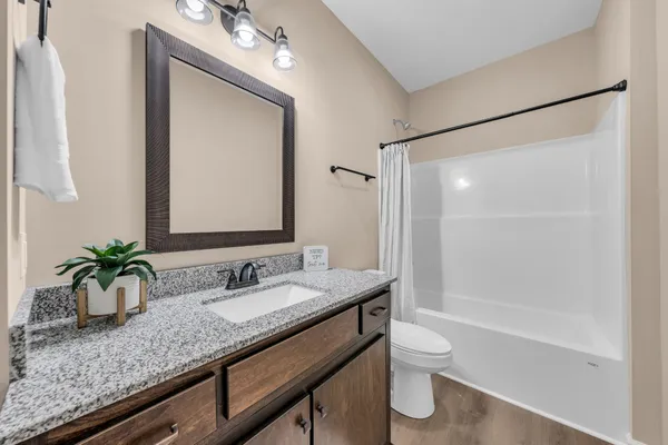 a bathroom with a granite countertop sink a toilet and shower