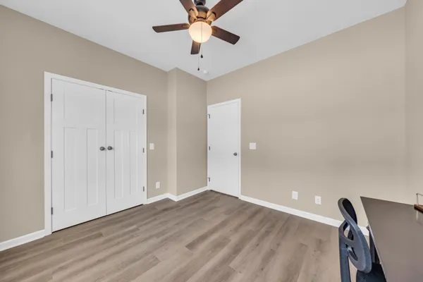 wooden floor in an empty room with a chandelier fan