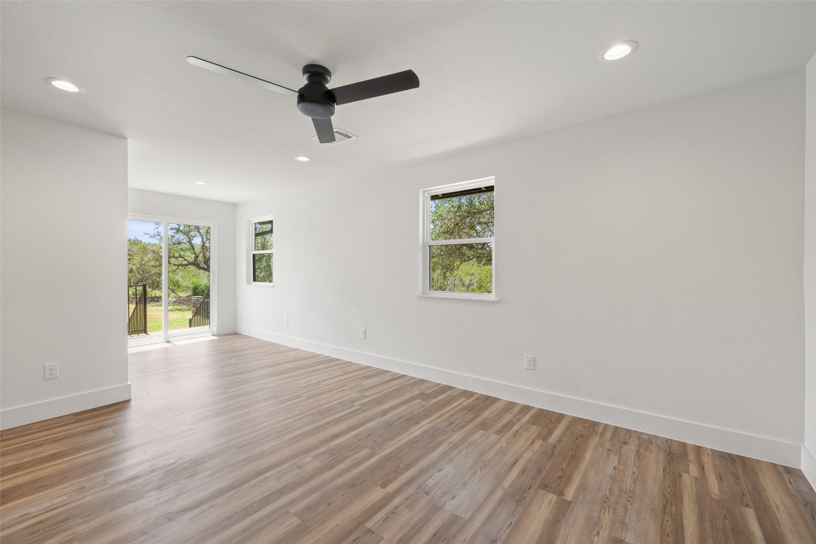 11151 Highway 71 Spicewood, TX 78669 - Photo 13 of 40 Unit A – Spacious primary bedroom with light wood-style LVP flooring and a private sitting area.