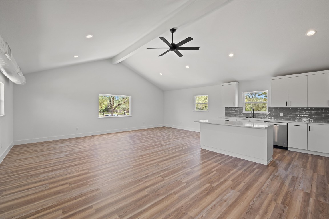 11151 Highway 71 Spicewood, TX 78669 - Photo 30 of 40 Unit C – Open-concept living, dining, and kitchen showcasing a vaulted ceiling, white cabinetry, center island, light wood-style flooring, recessed lighting, and expansive second-floor Hill Country views.