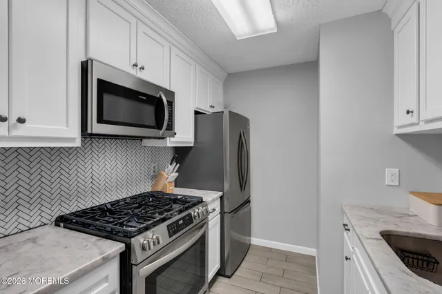 a kitchen with white cabinets and stainless steel appliances