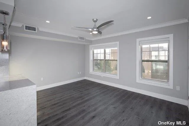 an empty room with wooden floor ceiling fan and windows