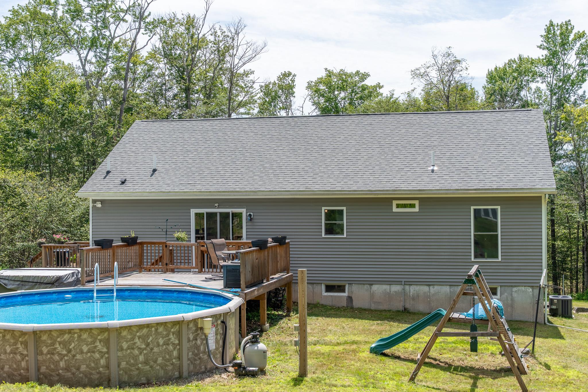 56 Ahrens Road Parksville, NY 12768 - Photo 17 of 23 Back of house featuring a wooden deck, an outdoor pool, a yard, roof with shingles, and a playground