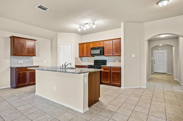 a kitchen with stainless steel appliances granite countertop a stove top oven a sink a counter top space and cabinets