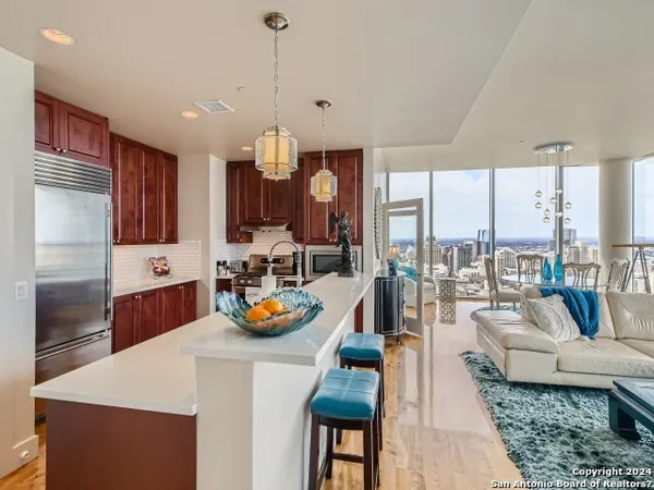 a living room with furniture kitchen view and a large window