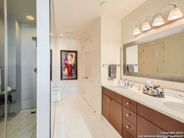 a bathroom with a double vanity sink mirror and shower
