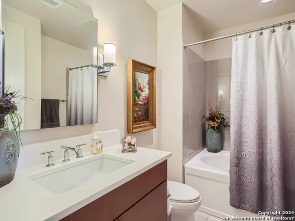 a bathroom with a sink a toilet a mirror and shower