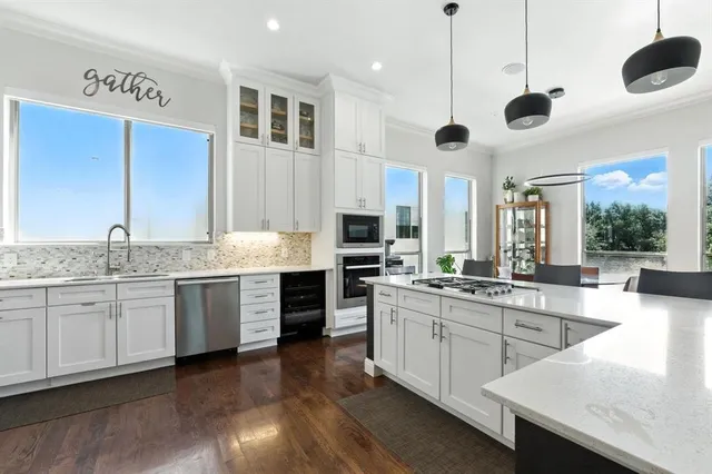 a large kitchen with stainless steel appliances granite countertop stove a sink dishwasher and a refrigerator with wooden floor