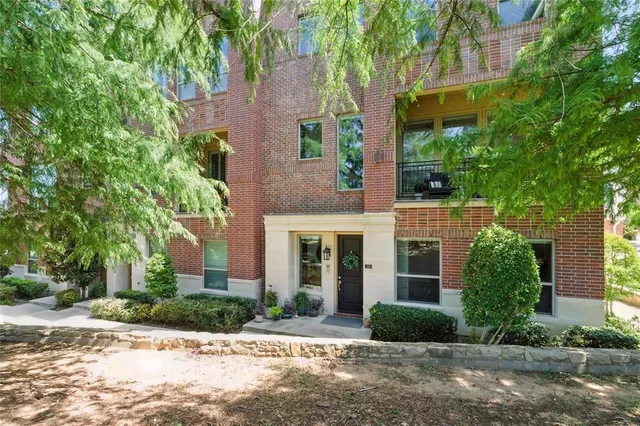 front view of a brick house with a yard and large trees