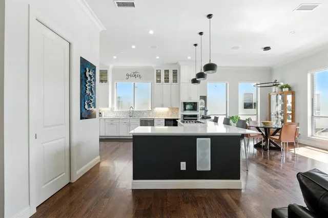 a large white kitchen with stainless steel appliances granite countertop a stove and wooden floor