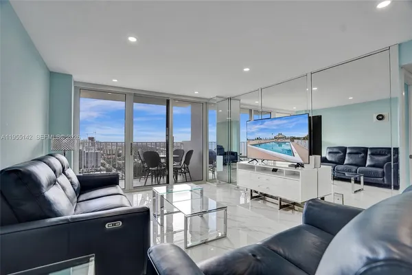 a living room with furniture a flat screen tv and a floor to ceiling window