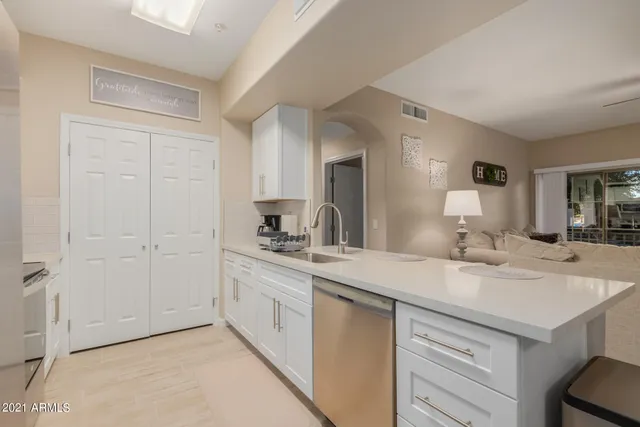 a view with granite countertop a sink and dishwasher with white cabinets