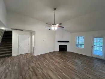 an empty room with windows and ceiling fan