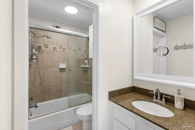 a bathroom with a granite countertop sink a toilet and shower