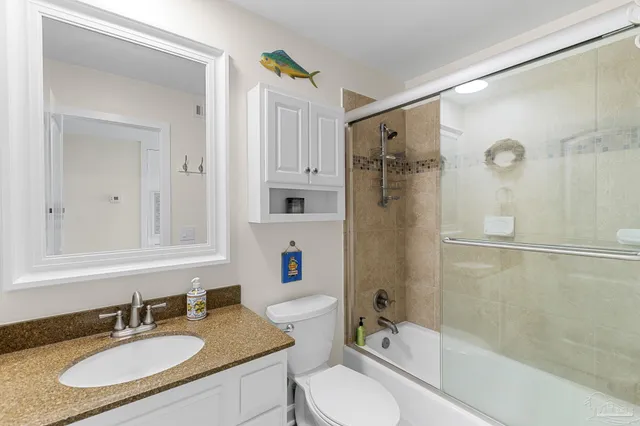 a bathroom with a granite countertop sink toilet mirror and shower