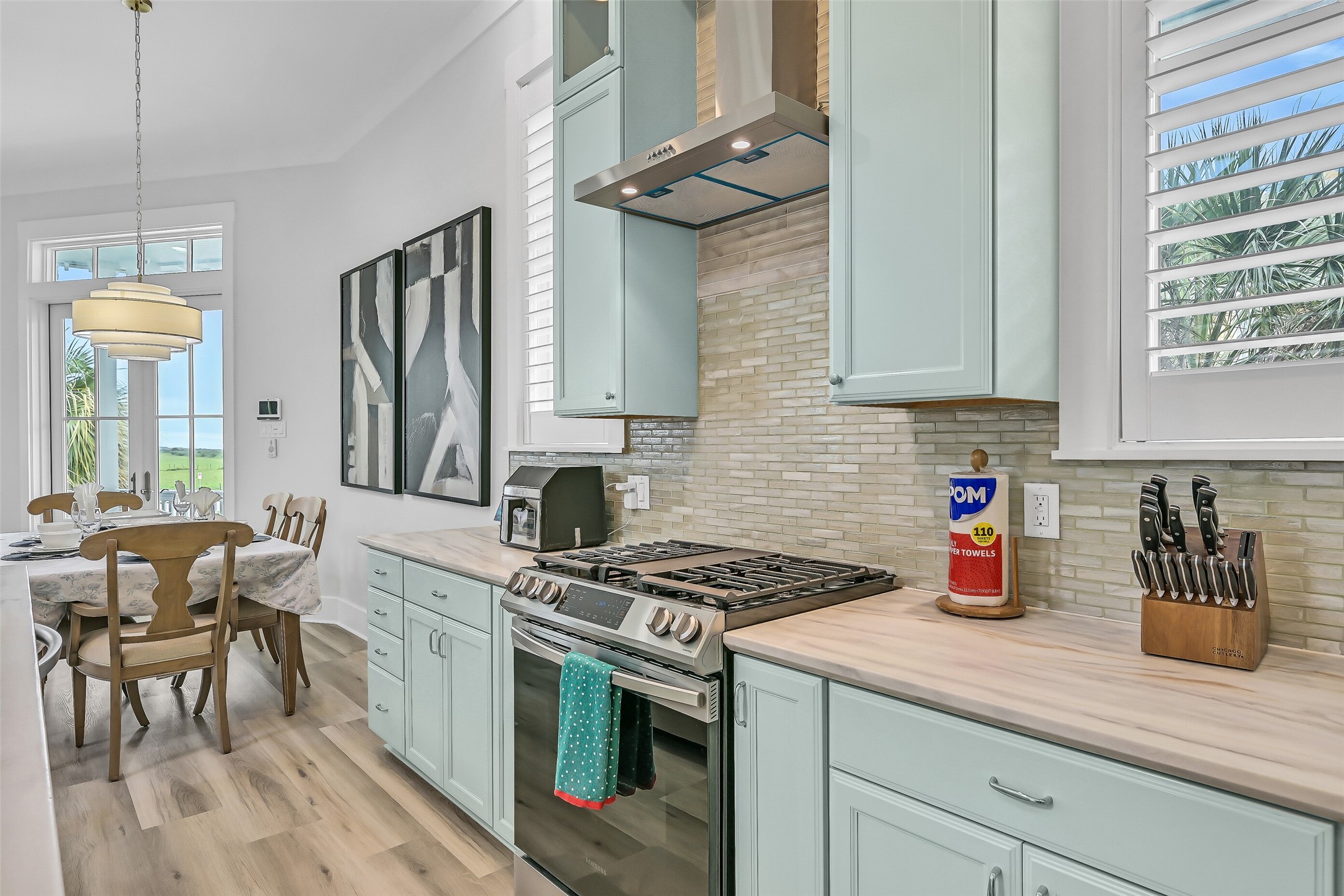 817 Positano Road Galveston, TX 77550 - Photo 17 of 50 The chef's kitchen showcases gas cooking, custom coastal cabinetry, generous prep space, a designer tile backsplash, and a recently upgraded range hood system. Thoughtful enhancements create a polished, custom feel while blending style, functionality, and everyday convenience.