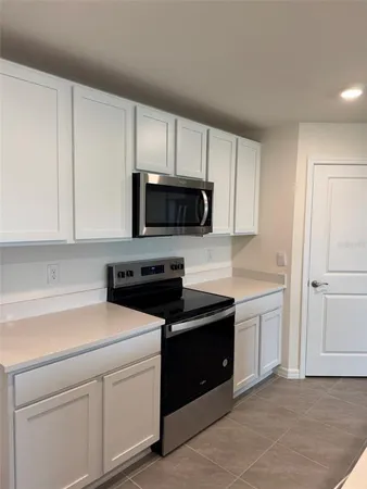 a kitchen with white cabinets and black appliances