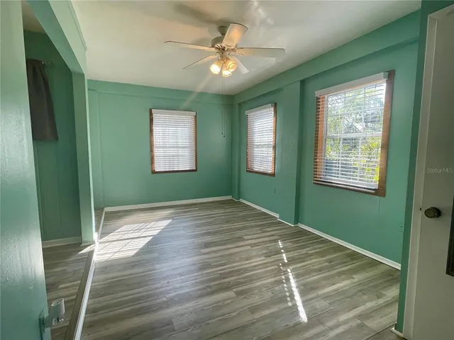 a view of an empty room with a window and a chandelier fan