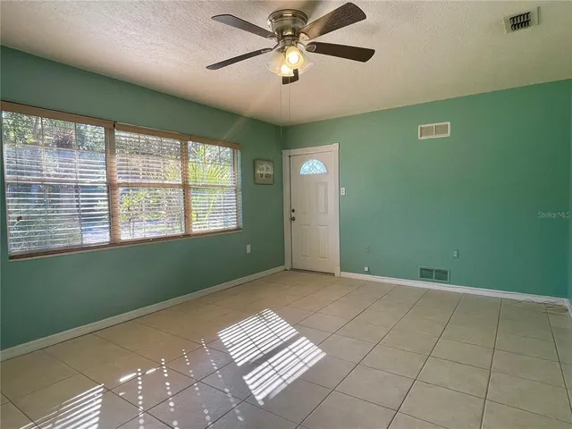a view of an empty room with a window and a kitchen