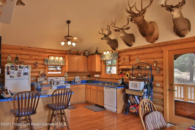 a kitchen with stainless steel appliances granite countertop a dining table chairs sink and a window