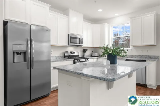 a kitchen with stainless steel appliances granite countertop a refrigerator a sink a stove a microwave and island