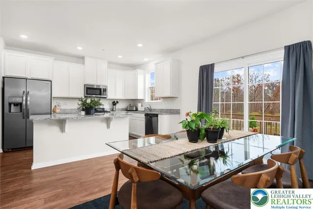 a kitchen with stainless steel appliances granite countertop a stove a refrigerator a sink a dining table and chairs