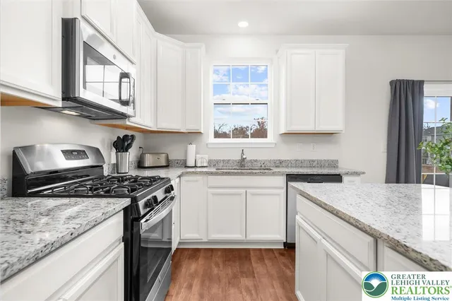 a kitchen with stainless steel appliances granite countertop a stove a sink dishwasher and cabinets with wooden floor