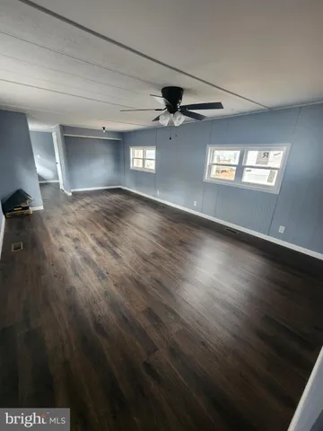 an empty room with wooden floor ceiling fan and windows
