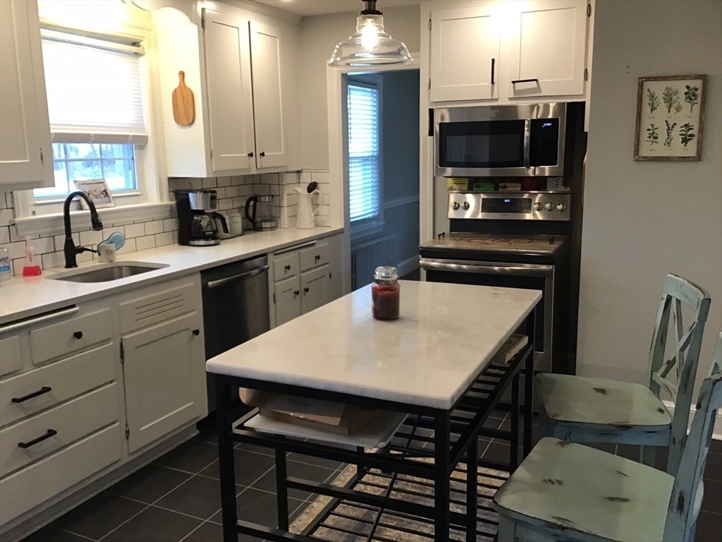 2 Coolidge Road Woburn, MA 01801 - Photo 2 of 24 a kitchen with a table chairs refrigerator and microwave