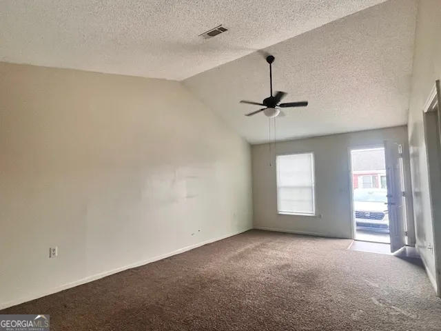 an empty room with windows and ceiling fan