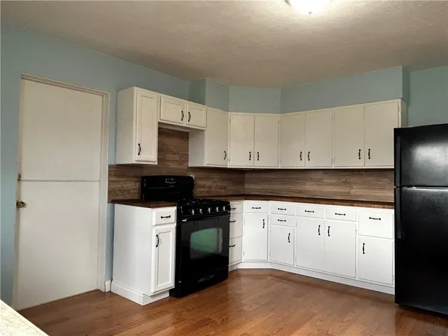a kitchen with granite countertop white cabinets and black appliances