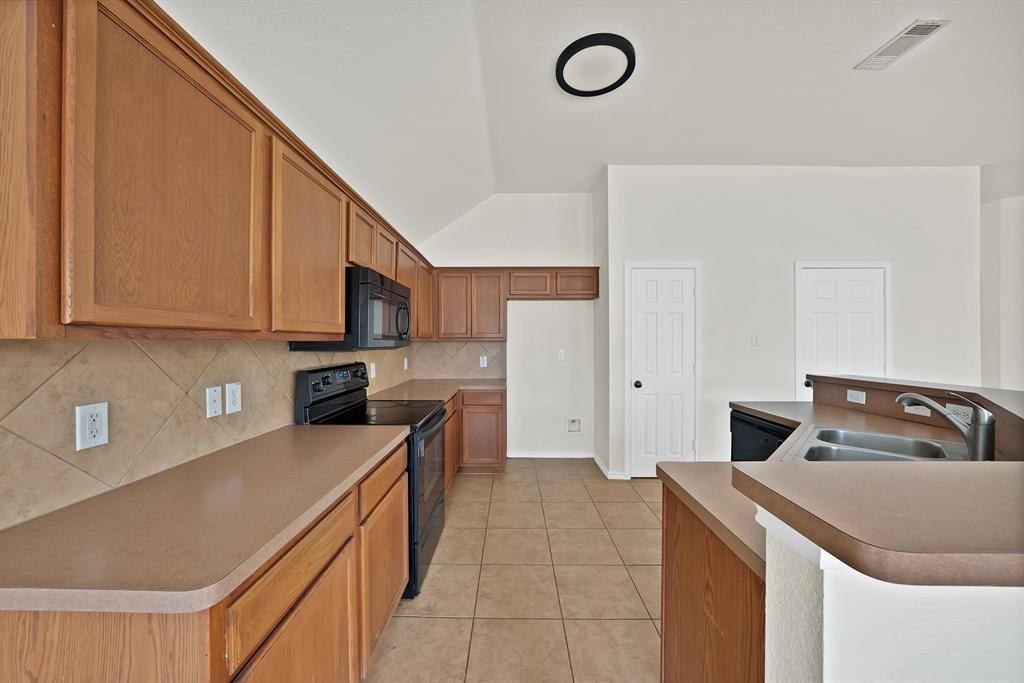 2832 Lone Ranger Trail Little Elm, TX 75068 - Photo 10 of 35 a kitchen with stainless steel appliances granite countertop a sink a stove a refrigerator a microwave oven with white cabinets