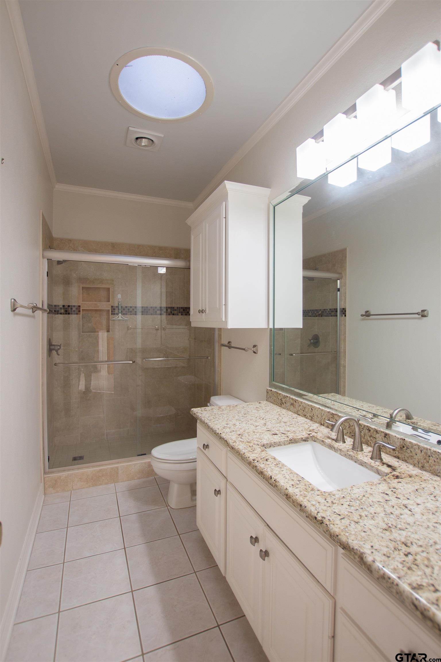 704 Shiloh Ridge Street Tyler, TX 75703 - Photo 11 of 34 a bathroom with a granite countertop sink a toilet a mirror and shower