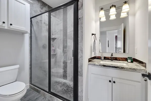 a kitchen with stainless steel appliances kitchen island granite countertop a stove a sink dishwasher a refrigerator and white cabinets with wooden floor