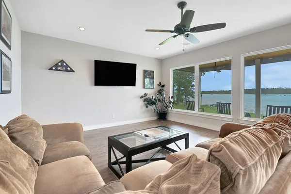 an empty room with wooden floor chandelier fan and windows