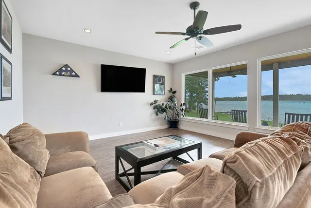 an empty room with wooden floor chandelier fan and windows