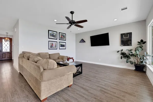 an empty room with wooden floor ceiling fan and window